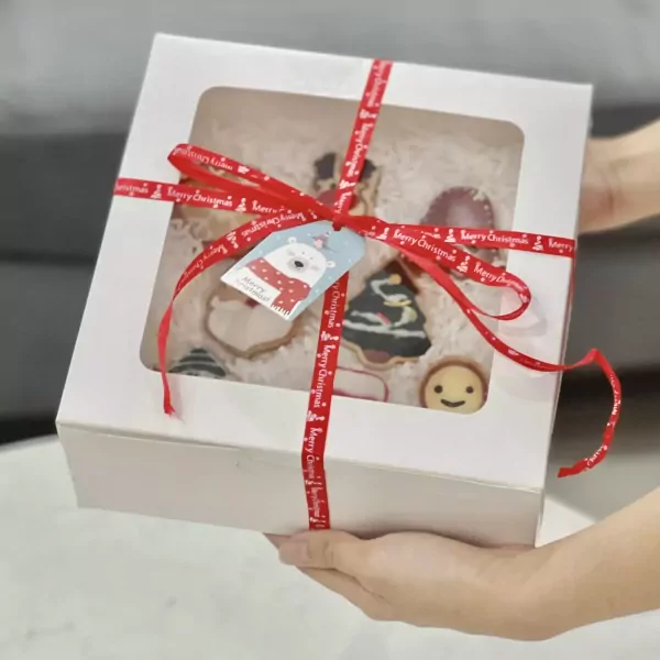 Christmas-themed cookie gift box with red ribbon and polar bear tag.