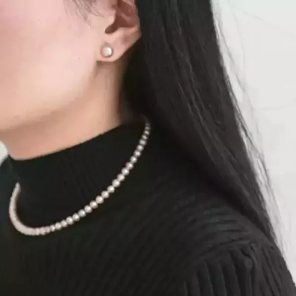 Woman wearing a high-quality pearl necklace and pearl stud earrings.