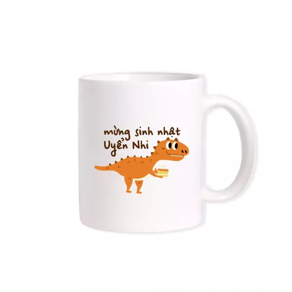 White mug with orange dinosaur holding a cake and "Mừng sinh nhật Uyển Nhi" text.