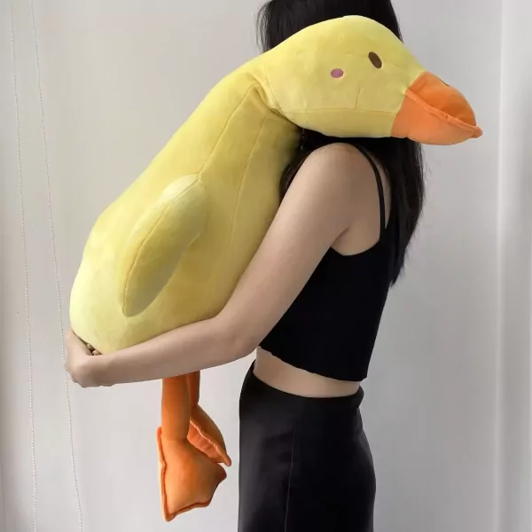 Large yellow duck plush toy with orange feet held by a person.