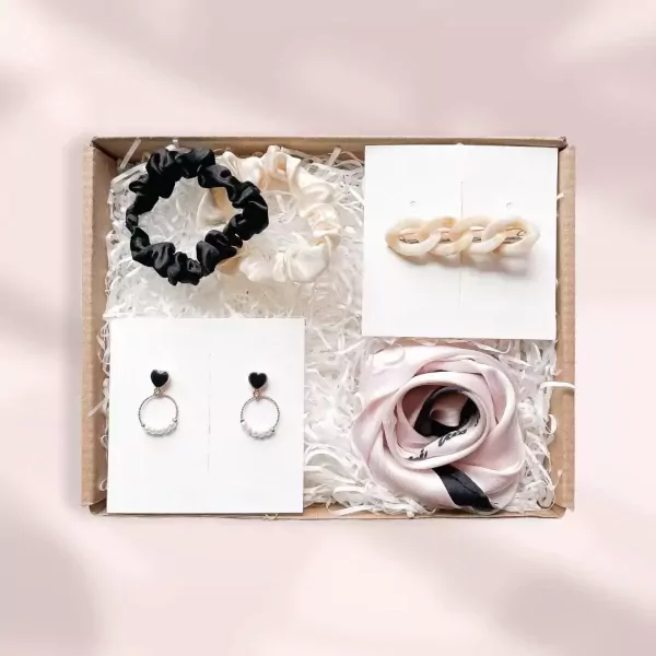 Gift box with scrunchies, earrings, hairpin, and scarf in neutral colors.