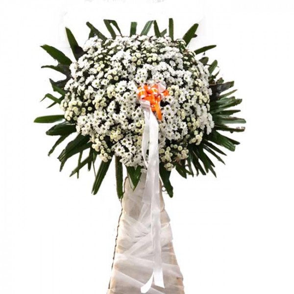 Standing funeral flower arrangement with white chrysanthemums and green leaves.