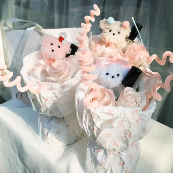 Bouquet of pink and white plush teddy bears nestled in paper flowers with decorative pink swirls.