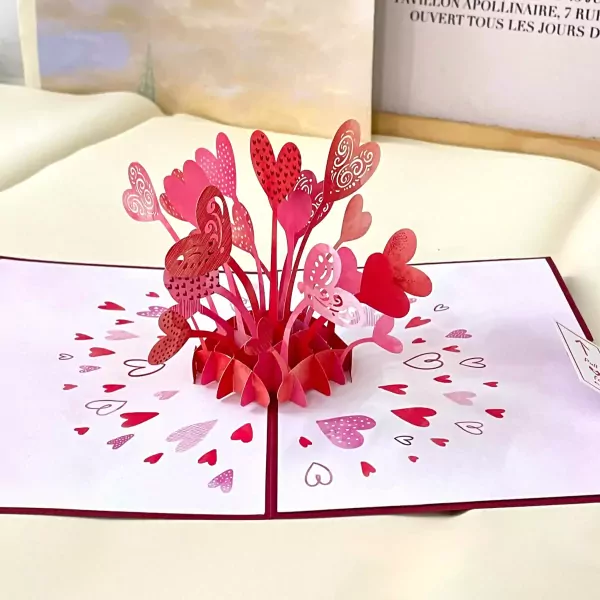 A 3D pop-up card with a bouquet of red and pink hearts exploding from the center.