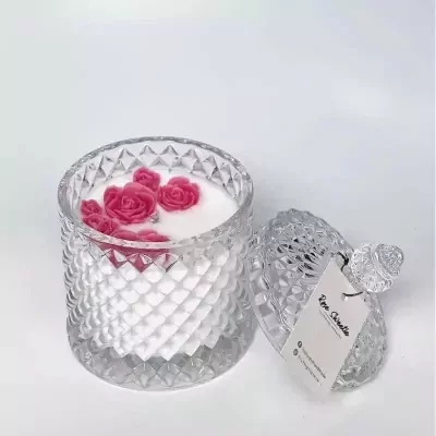 Glass jar candle with pink rose wax melts on top, lid ajar with tag.