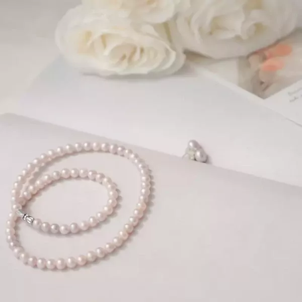 Pearl necklace and earrings with white roses in the background.