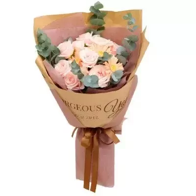 A bouquet of pink and white roses with eucalyptus leaves, wrapped in brown and pink paper.