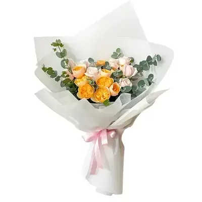 Bouquet of peach and cream roses with eucalyptus, wrapped in white paper and tied with a pink ribbon.