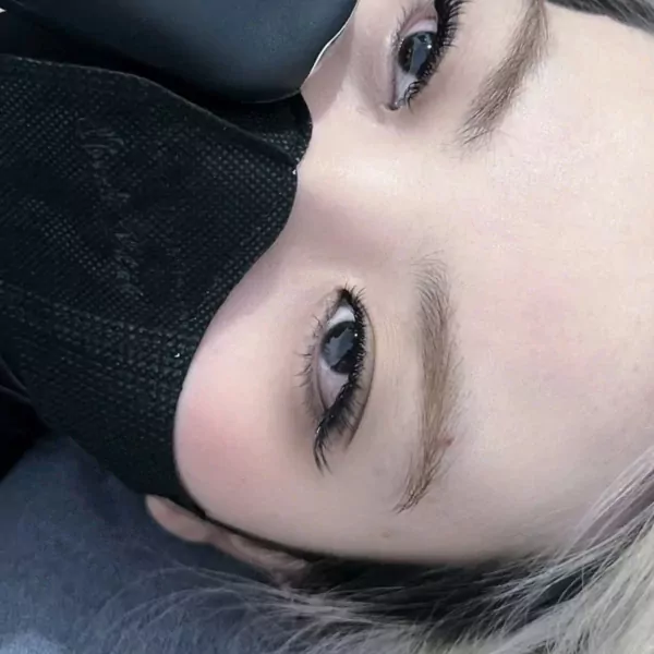 Close-up of a person's eyes with a black mask covering their nose and mouth.