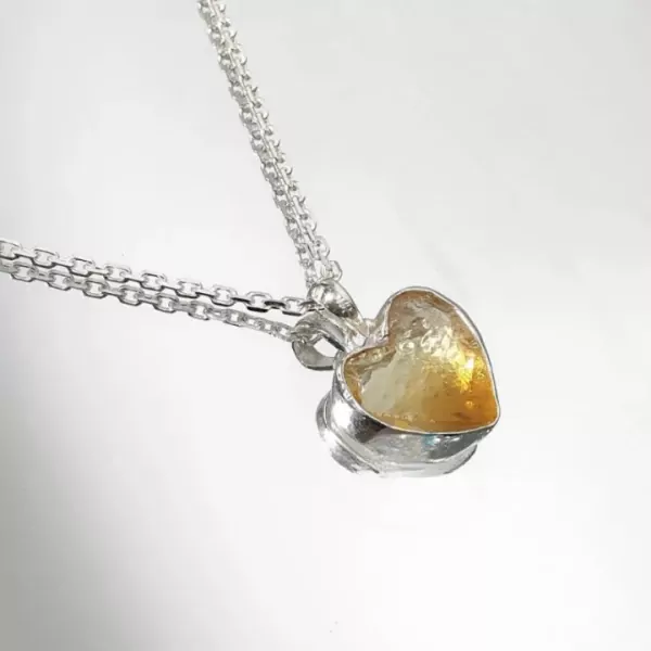Silver necklace with a heart-shaped, translucent amber-colored stone.