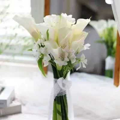 White calla lily and alstroemeria wedding bouquet tied with lace ribbon.