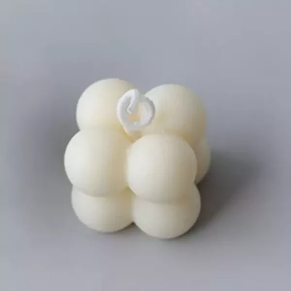 White bubble candle with a white wick on a grey background.