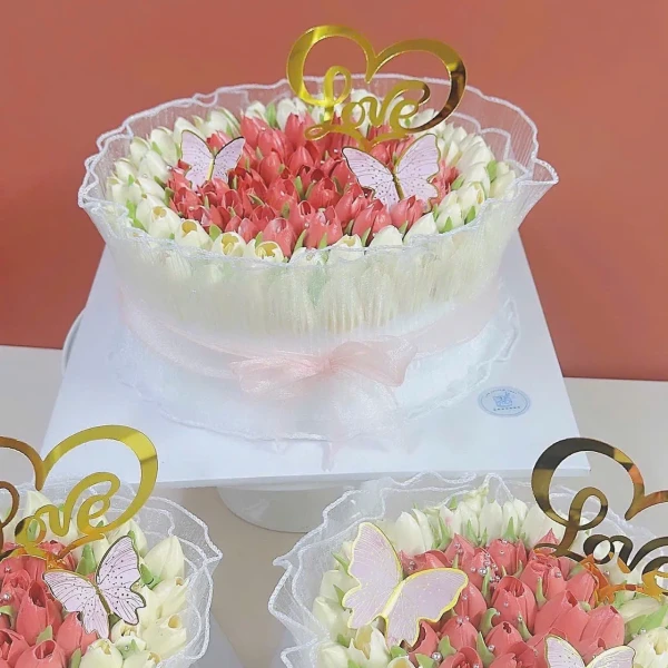 Two romantic cakes decorated with pink and white frosting flowers and butterflies.