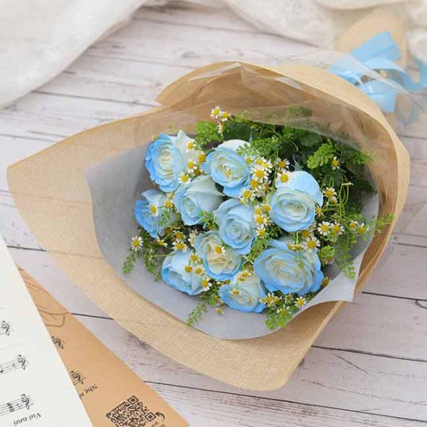 Bouquet of blue roses with white accents and greenery, wrapped in burlap.