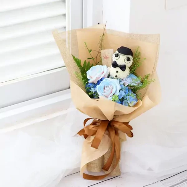 Bouquet with a teddy bear dressed as a teacher, surrounded by blue and pink roses and hydrangeas.