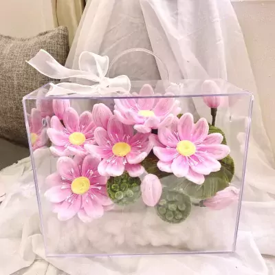 Pink lotus flowers in a clear box with white ribbon.