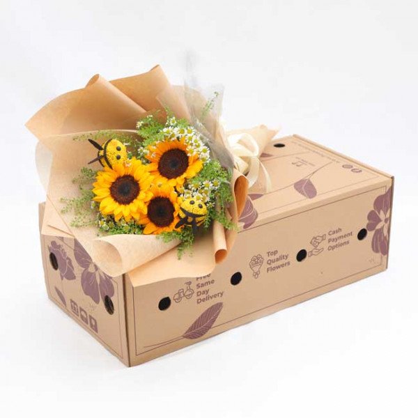 Sunflower and daisy bouquet with bee decorations in a cardboard box.