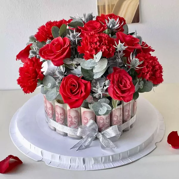 Red roses and carnations in a money cake with silver ribbon.