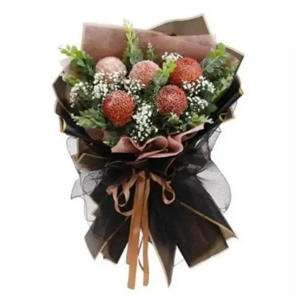 A bouquet of brown peony chrysanthemums with baby's breath and eucalyptus leaves, wrapped in black and brown paper, tied with a ribbon.