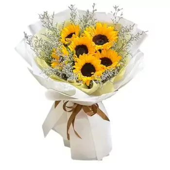 Bouquet of sunflowers and purple statice flowers, wrapped in white paper and tied with a brown ribbon.