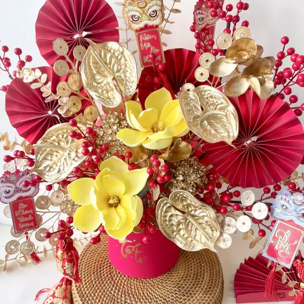 Red and gold floral arrangement with lucky coins, magnolias, and anthuriums for Lunar New Year.
