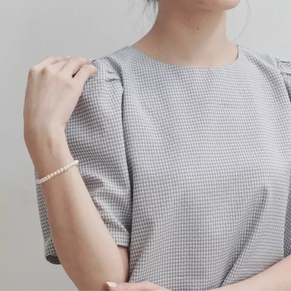 Close-up of a person's arm wearing the Azure Pearl Bracelet on a light background.