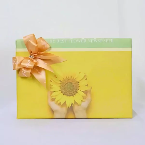 Yellow gift box with a sunflower, peach ribbon, and "The Best Flower Newspaper" text.