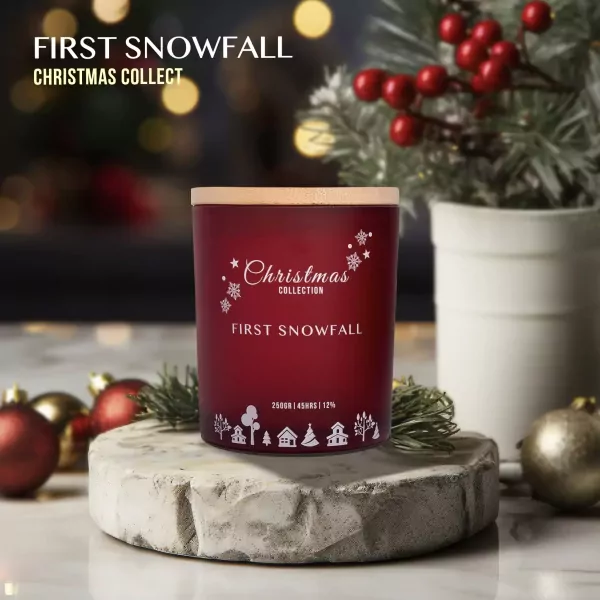 Red Christmas candle labeled "First Snowfall" with snowflake and village designs.