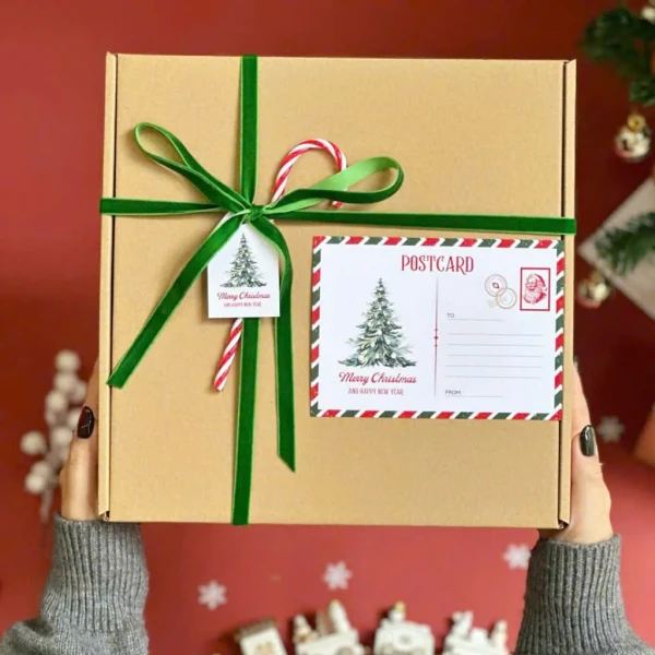 Christmas gift box with green ribbon, candy cane, tag, and postcard.