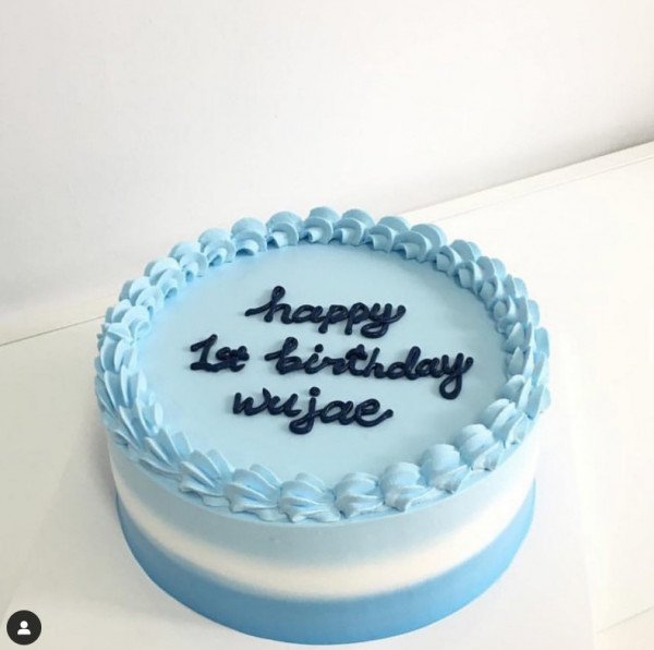 Blue ombre cake with "happy 1st birthday wujae" written in navy blue frosting.