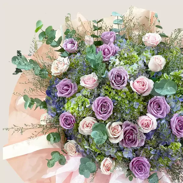 A bouquet of purple and pink roses, hydrangeas, eucalyptus, and filler flowers.