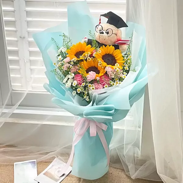 Graduation bouquet with sunflowers, pink carnations, baby's breath, and a graduation teddy bear.