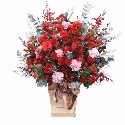 Vase of red roses and pink carnations with eucalyptus leaves, tied with a brown ribbon.