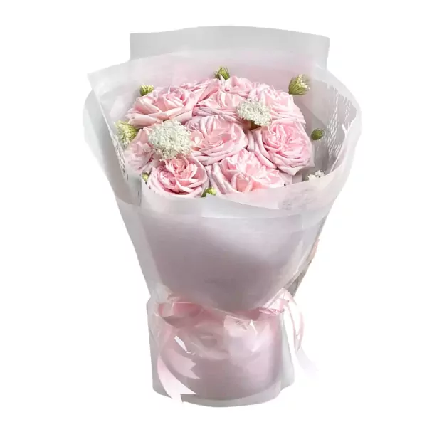 Bouquet of pale pink roses with delicate white filler flowers, wrapped in white and pink paper, tied with a pink ribbon.
