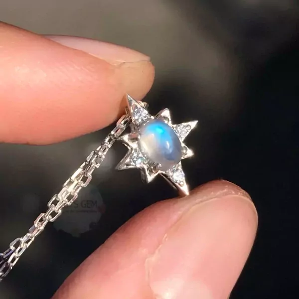 Star-shaped pendant necklace with moonstone and diamonds on a silver chain, held by fingers.