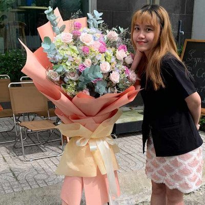 Woman with a large bouquet of pink, purple, and white flowers.