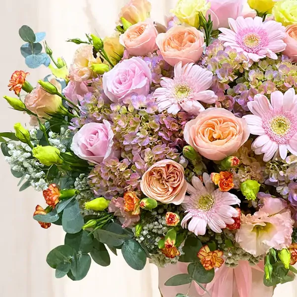A lush bouquet of pink and peach roses, gerbera daisies, hydrangeas, and greenery.