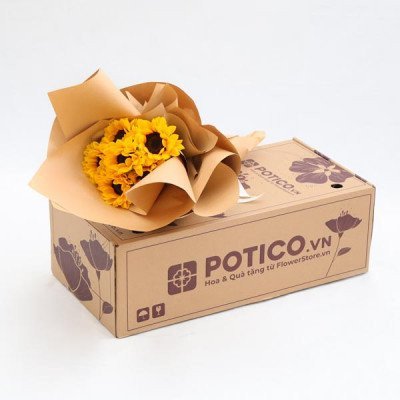A bouquet of sunflowers wrapped in brown paper sits on a cardboard box.