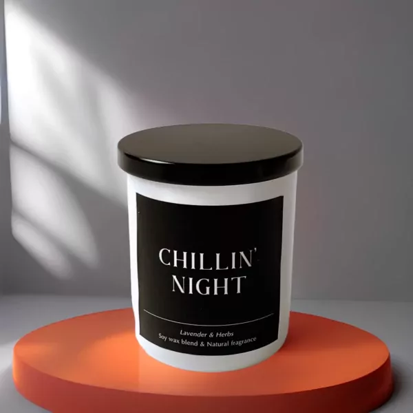 White candle with black label saying "CHILLIN' NIGHT" on an orange circular stand.
