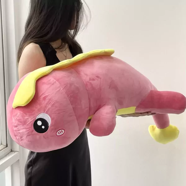 Large pink plush dinosaur toy with yellow accents, held by a person.