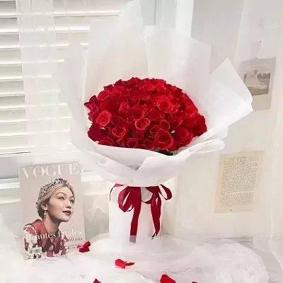 A large bouquet of 66 red roses, wrapped in white paper and tied with a red ribbon.
