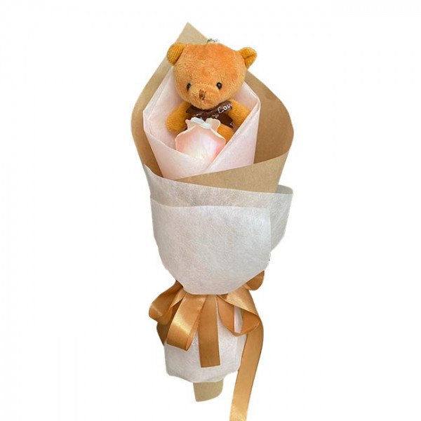 Small teddy bear and pink rose bouquet wrapped in brown and white paper, tied with a gold ribbon.