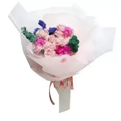 Bouquet of pink roses, purple flowers, and green foliage wrapped in white paper with a pink ribbon.