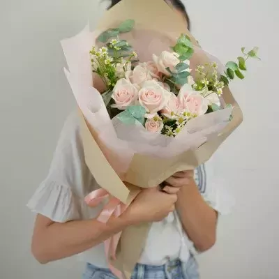 Woman holding a bouquet of pink roses and white flowers.