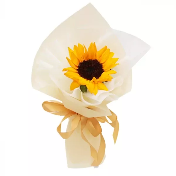 A single sunflower in a bouquet with sheer cream paper wrapping and a golden ribbon.