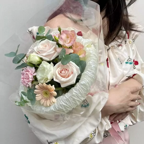 A bouquet of pink and cream roses, carnations, and gerbera daisies.