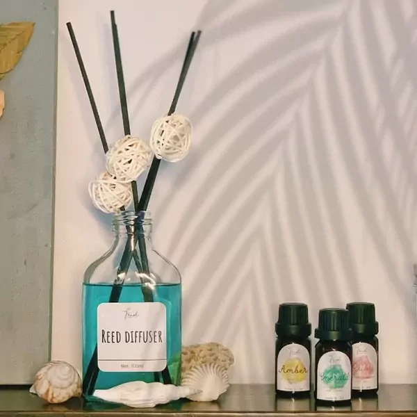 Reed diffuser with blue liquid and decorative balls, three small essential oil bottles.