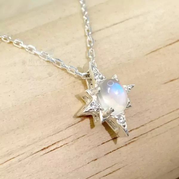 Star-shaped necklace with moonstone and diamonds on a wooden surface.