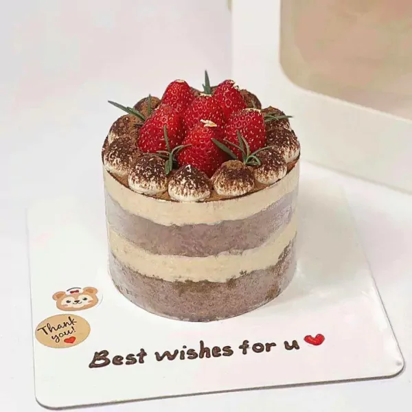 Tiramisu cake topped with fresh strawberries and dusted with cocoa powder.