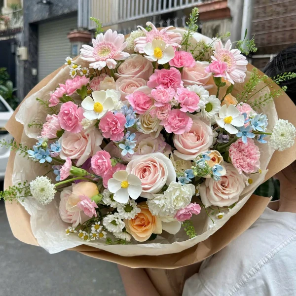 A romantic bouquet of pink and cream roses, carnations, and daisies.
